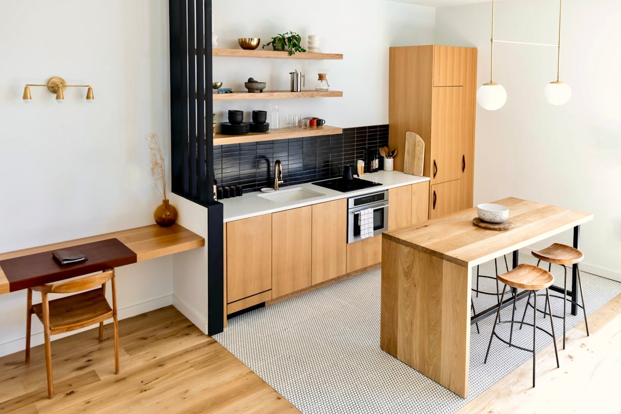 Light-filled modern kitchen interior with wooden furnishings and black accents.